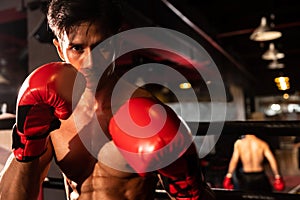 Muay Thai boxer punch his fist in front of camera posing. Impetus