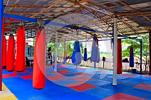 Muay Thai gym with boxing bags and colorful rubber floor at Ban Bung Sam Phan Nok, Phetchabun, Thailand.