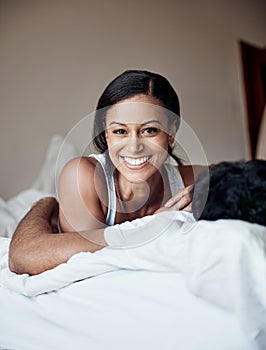 So much love. Portrait of a young woman lying on a bed with her husband at home.