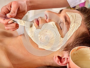 Mud facial mask of man in spa salon. Deep cleansing massage.