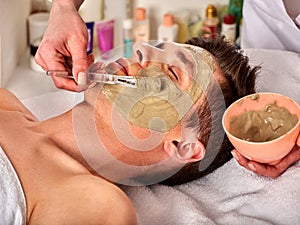 Mud facial mask of man in spa salon. Face massage .