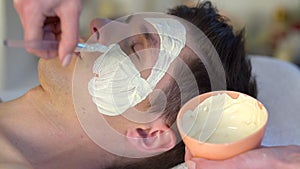 Mud facial mask of man in spa salon. Face massage .