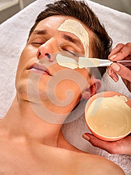 Mud facial mask of man in spa salon. Face massage .