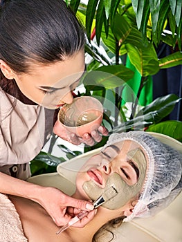 Mud facial mask of woman in spa salon. Cleansing purifying.