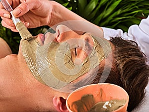 Mud facial mask of woman in spa salon. Face massage .