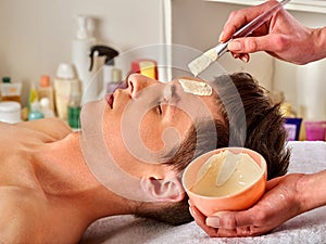 Mud facial mask of woman in spa salon. Face massage .