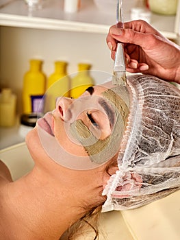 Mud facial mask of woman in spa salon. Face massage .