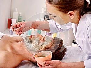 Mud facial mask of woman in spa salon. Face massage .