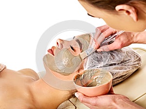 Mud facial mask of woman in spa salon. Face massage.