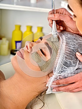 Mud facial mask of woman in spa salon. Face massage .