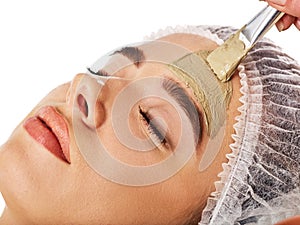 Mud facial mask of woman in spa salon. Face massage.