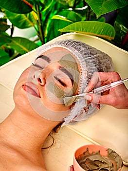 Mud facial mask of woman in spa salon. Face massage .