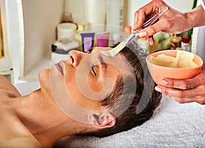 Mud facial mask of woman in spa salon. Face massage .