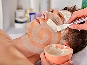 Mud facial mask of woman in spa salon. Face massage .