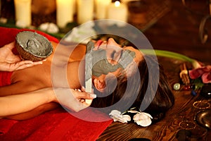 Mud facial mask of woman in spa salon. Face massage .