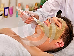 Mud facial mask of woman in spa salon. Face massage.