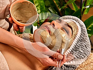 Mud facial mask of woman in spa salon. Face procedure .