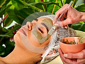 Mud facial mask of woman in spa salon. Face procedure .
