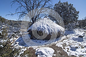 Mud hut survival shelter covered in snow