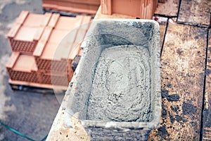 Mud pan with cement, mortar and tools for bricklaying on construction site photo