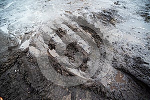 Mud with a puddle and traces of transport on an impassable road