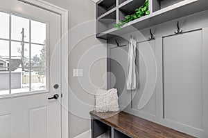 A mud room / entryway with a grey shelving and coat hooks.