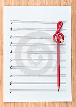 Blank sheet music end a red pencil in the shape of treble clef. Composing concept.