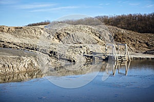 A mud volcano and a stream of grey clay from an eruption and gas escape. Cracked soil surface. Texture of a mudflow