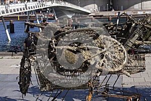 Muddy bicycles and shopping carts picked up from the bottom of the water in an urban harbor thrown into the water