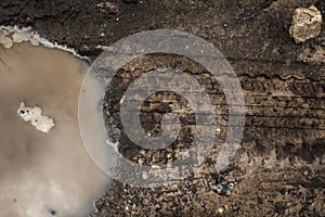 Muddy dirt road with puddles and tire tracks