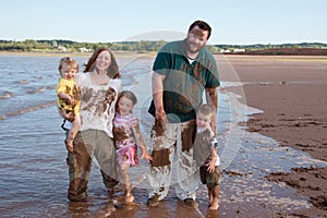 Muddy family playing on beach photo