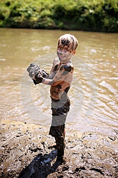 Muddy Little Boy Child Laughing as He Swims and Plays Outside in