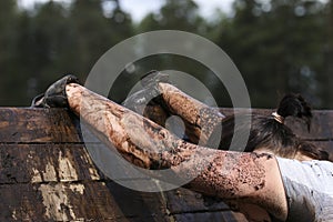 Muddy obstacle race runner in action. Mud run