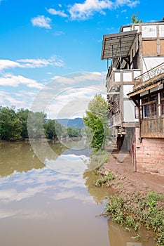 Muddy riverside path along dwelling buildings in sunny morning