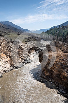 Muddy stream in mountain canyon. Yellow dirty river after flooding in early spring