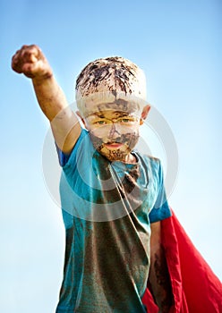 A muddy superhero. A little boy dressed as a superhero and covered in mud.