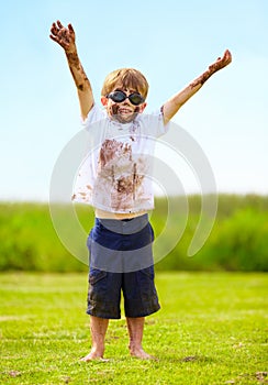 A muddy superhero. A little boy dressed as a superhero and covered in mud.