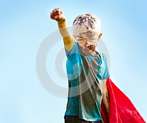 A muddy superhero. A little boy dressed as a superhero and covered in mud.