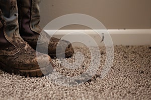 mudstained boots beside a clean carpet transition to filthy