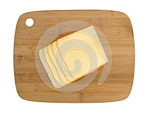 Muenster cheese slices on a wood cutting board