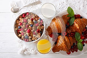 Muesli with berries and croissants, milk and orange juice close-