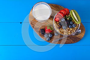 Muesli with berries and fruits on blue wooden background