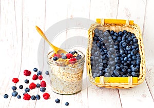 Muesli with blueberries in glass jar on white wooden background. The concept of a healthy breakfast.