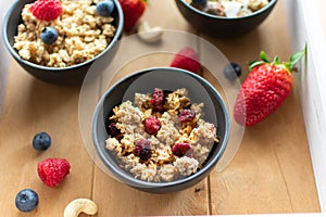 Muesli in a bowl with dried fruits on a wooden tray.