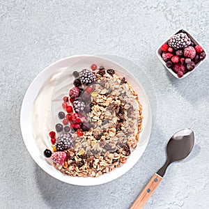 Muesli bowl or granola bowl with yogurt and berries on concrete table top. Healthy breakfast, top view. Dish suitable for diet,