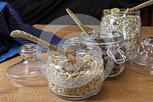 Muesli, breakfast cereal, oatmeal in a glass container and a cup of milk on a wooden table. Rustic food.