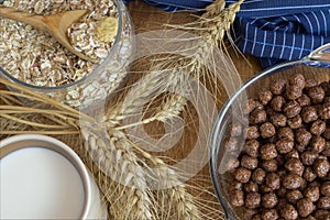 Muesli, breakfast cereal, oatmeal in a glass container and a cup of milk on a wooden table. Rustic food.