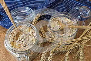 Muesli, breakfast cereal, oatmeal in a glass container on a wooden table. Rustic food.