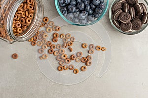 Muesli and cereals are scattered with jars of blueberries and sweet cookies on a light background, breakfast background.flat lay?