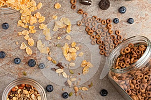 Muesli and cereals are scattered with jars of blueberries and sweet cookies on a light background, breakfast background.flat lay?